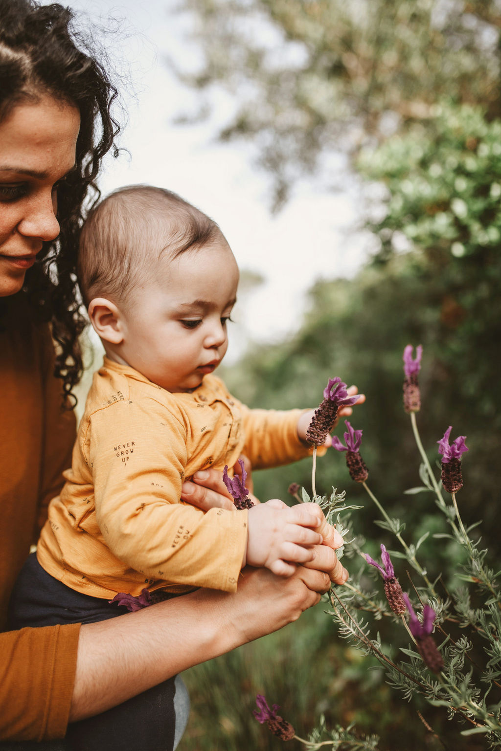 Humana Baby pflückt Blumen mit Mama