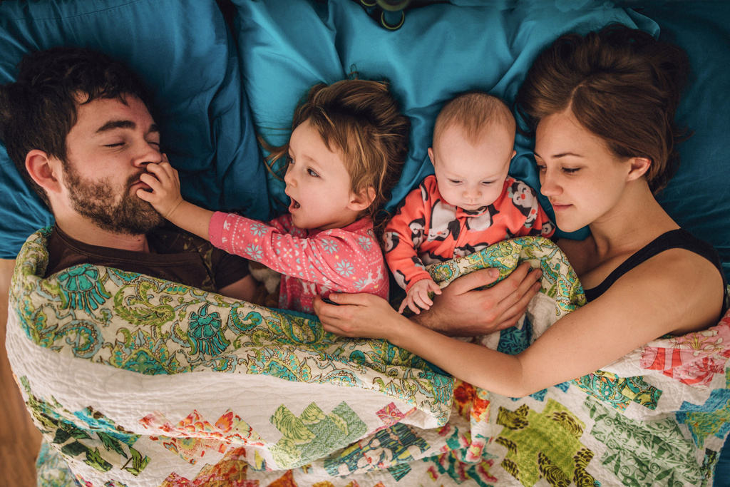 Family of four cuddling in bed 