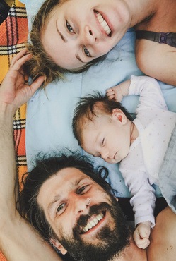 mom, dad and baby lying in bed together 