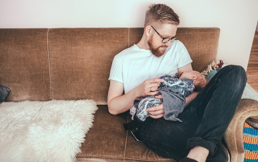 dad on the couch with sleeping baby on lap